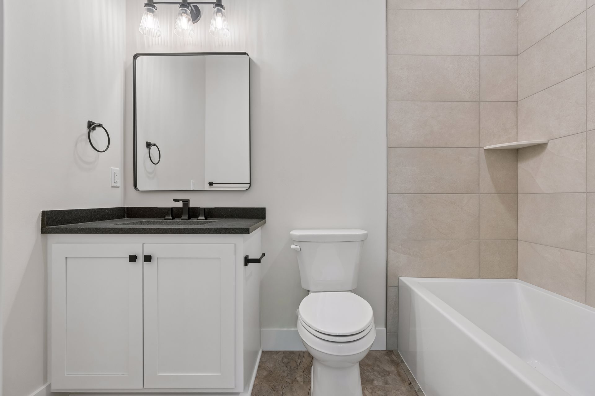 Additional bathroom with white vanity, black fixtures and tub shower surround
